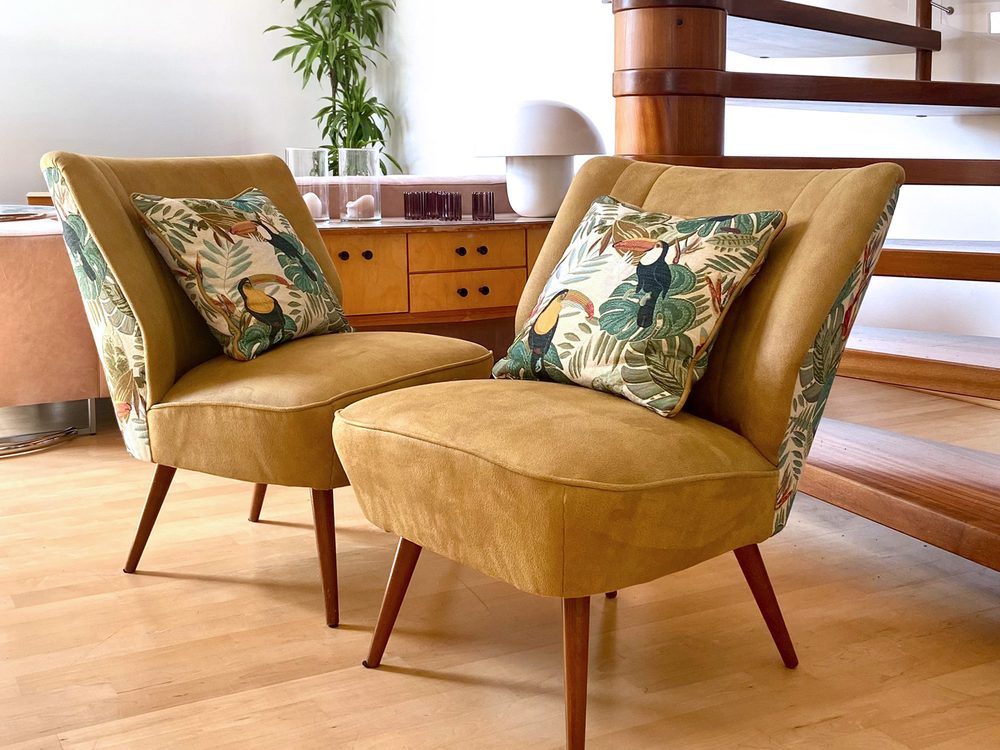 Zwei Cocktailsessel aus den 50er-Jahren in Senfgelb mit Tukan-Jacquard auf der Rückseite und passenden Kissen
