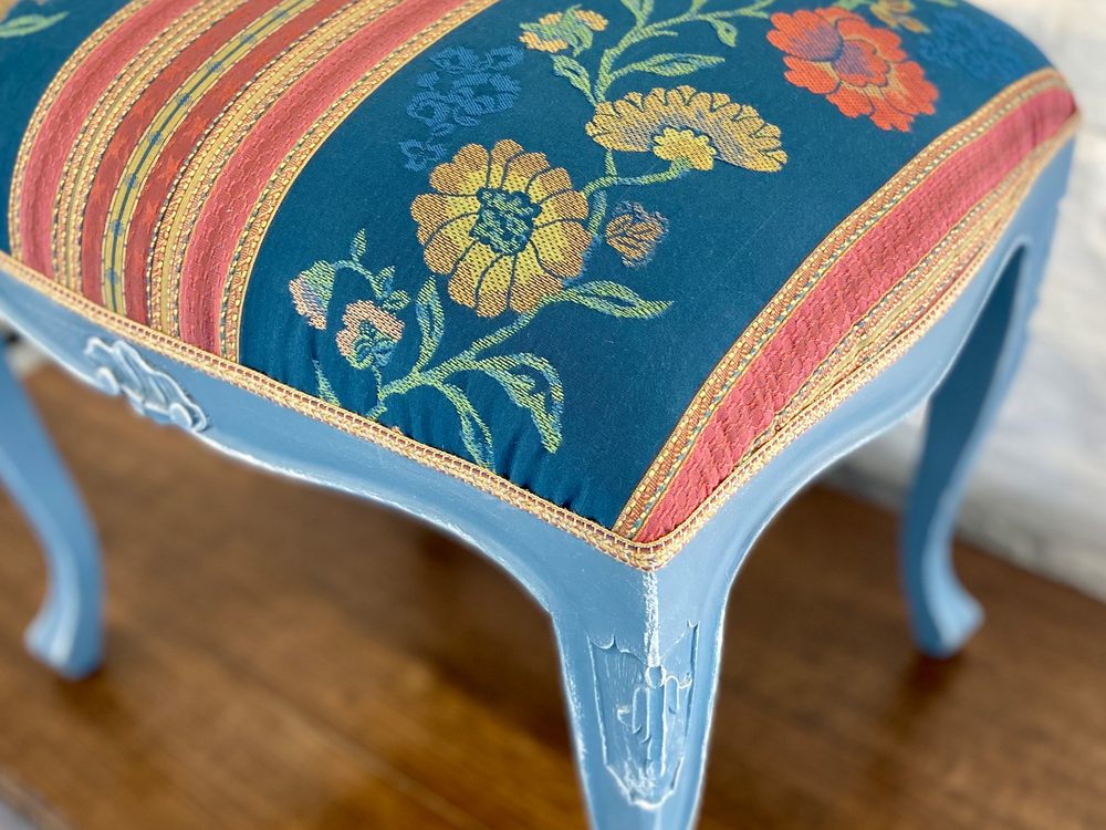 Hocker mit hellblau gestrichenen geschwungenen Beinen, neu bezogen mit blauem Blumen-Jacquard mit Streifen und Borte